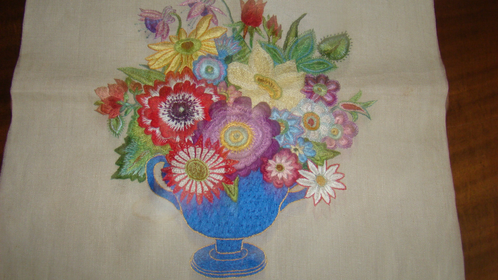 Geborduurde vaas met bloemen op linnen.