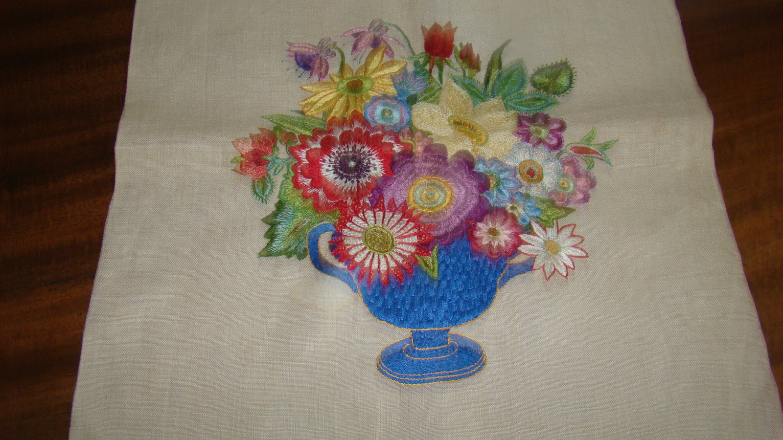 Geborduurde vaas met bloemen op linnen.