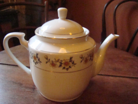 Witte theepot met gele bloemenrand.